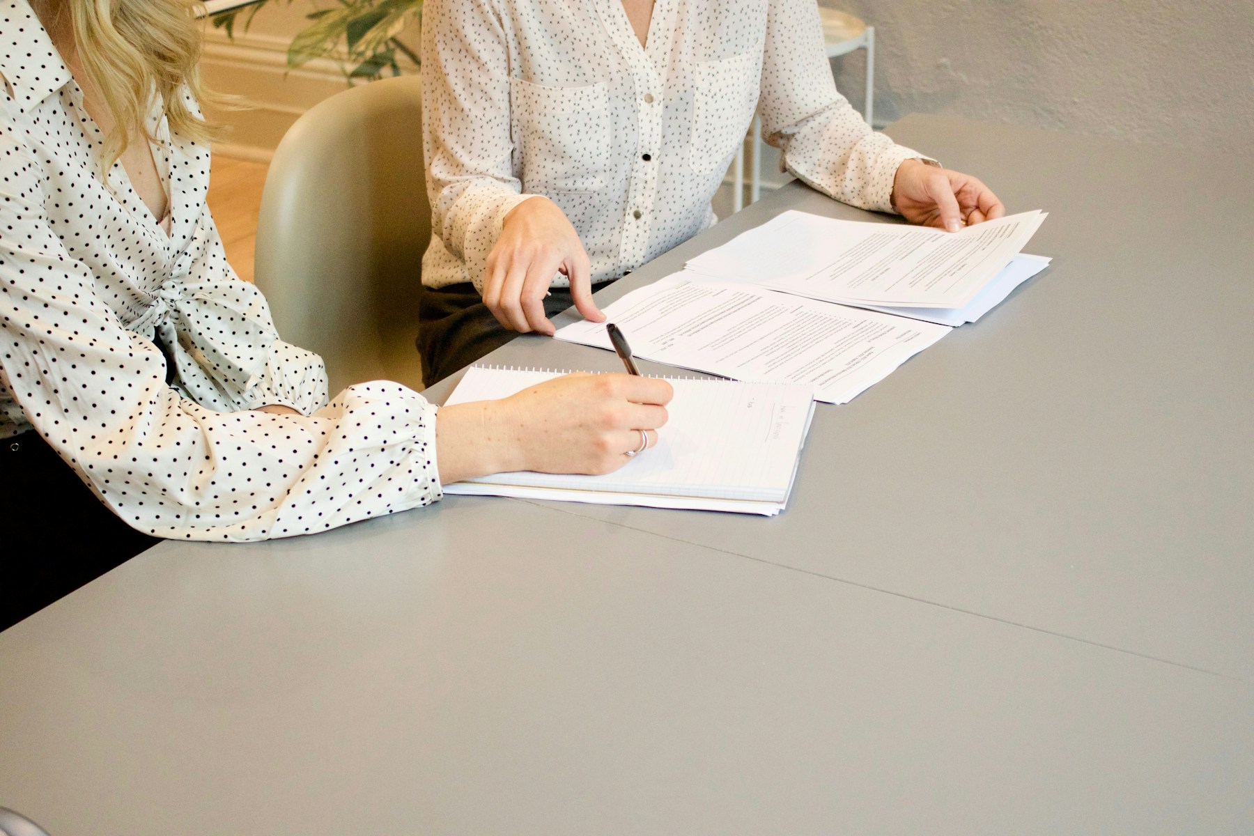 Two people reviewing and signing documents at a table